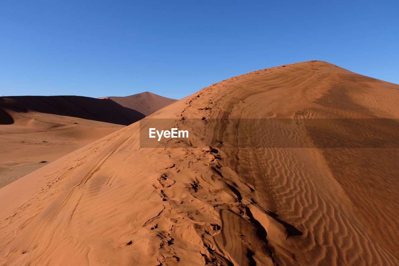 Sand dunes in desert against clear sky