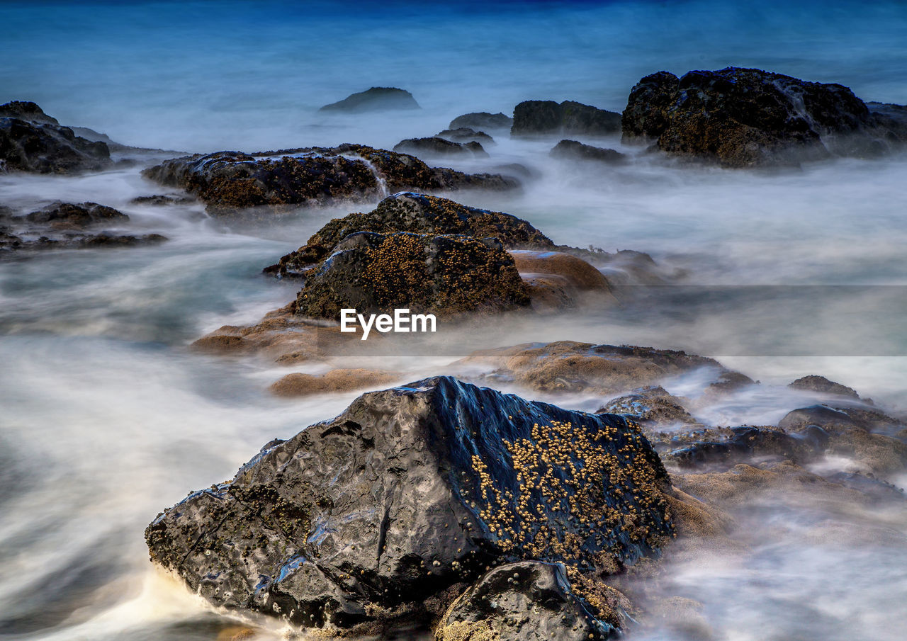 SCENIC VIEW OF ROCKS ON SEA AGAINST SKY