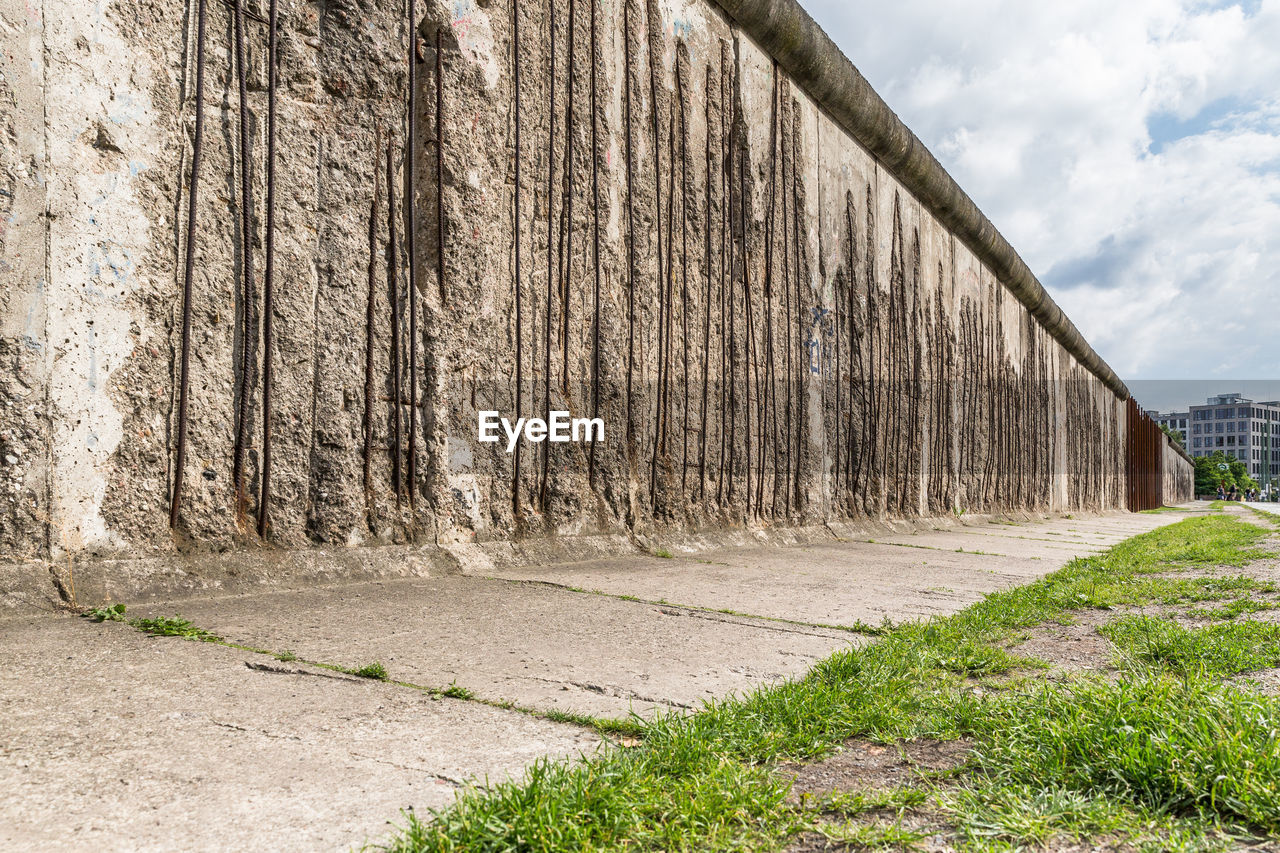 Damaged historic berlin wall against sky