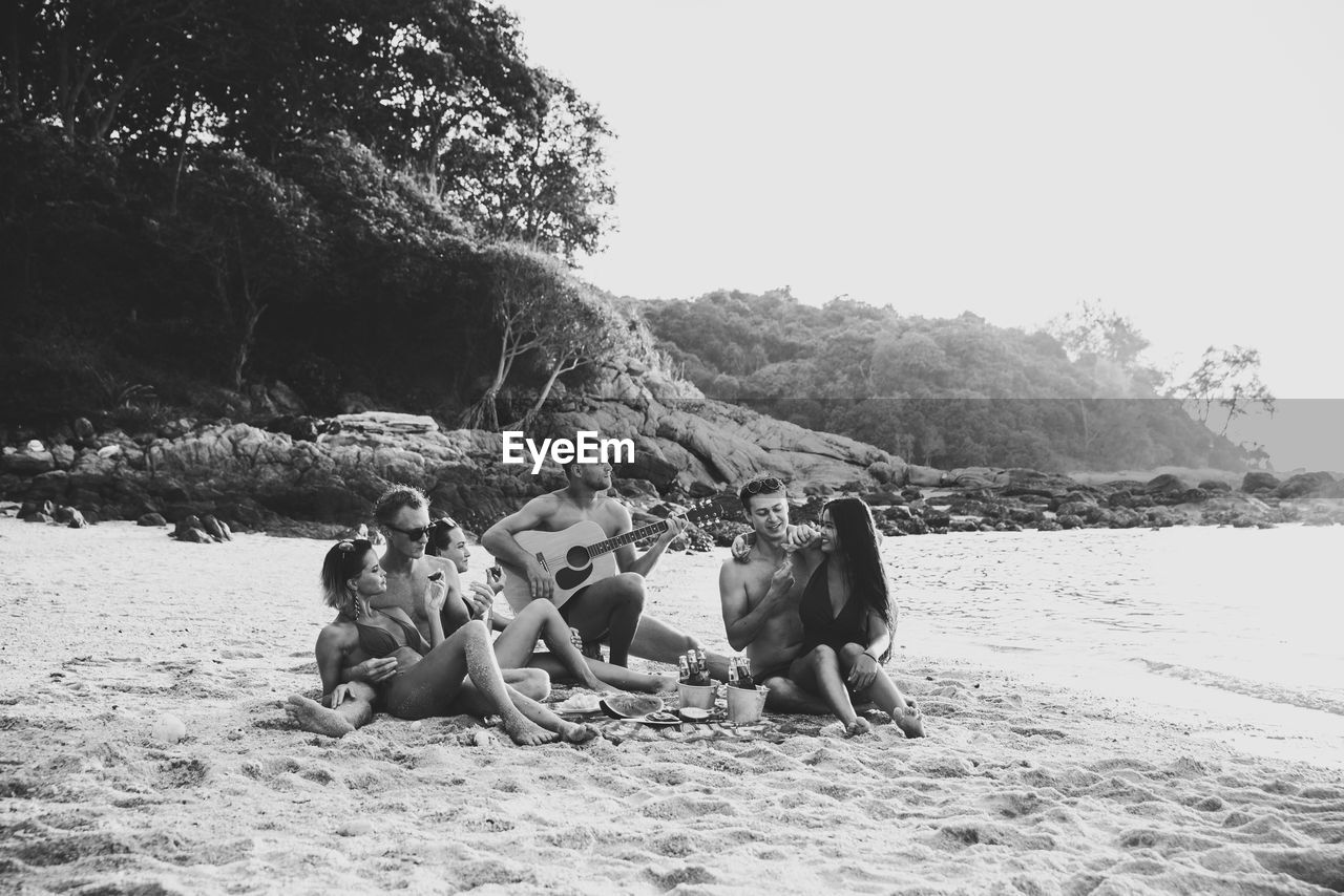 GROUP OF PEOPLE SITTING ON SHORE