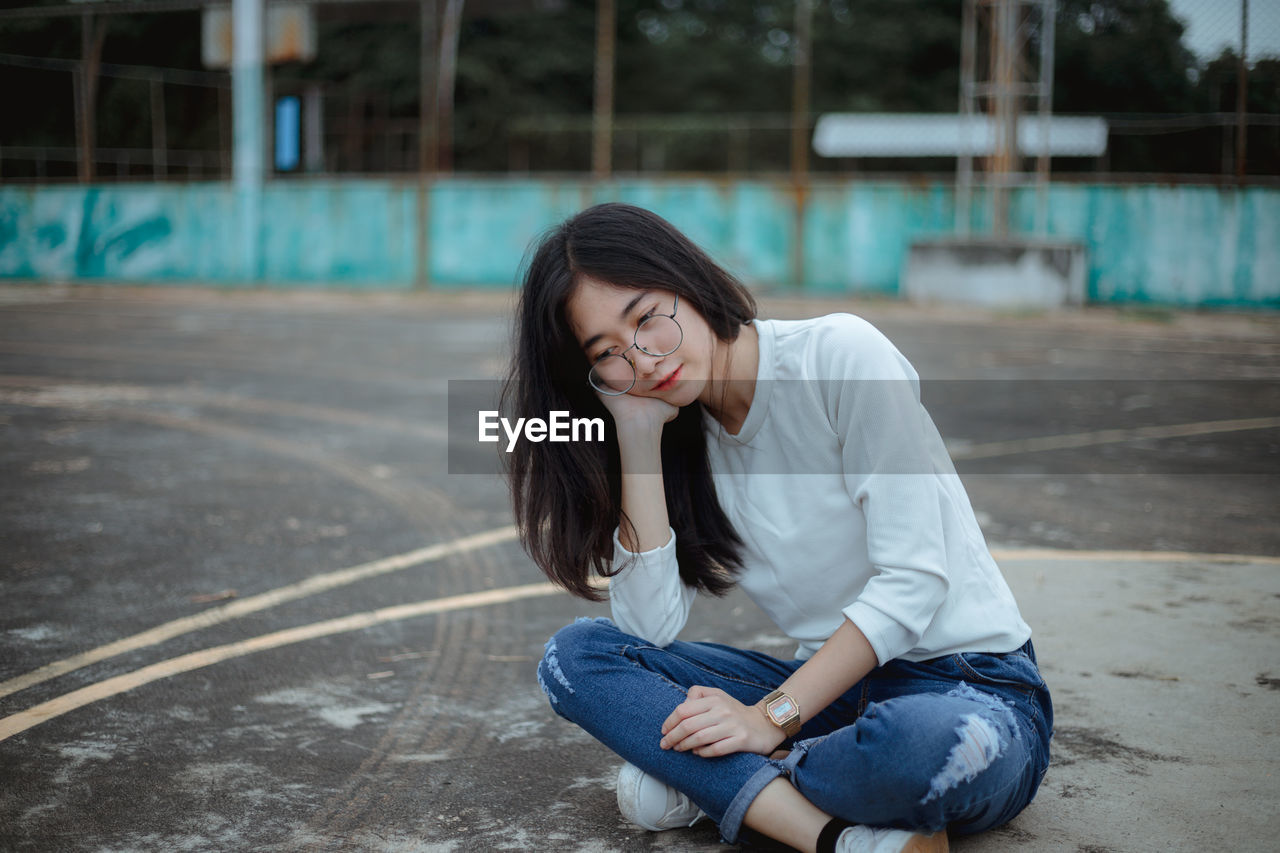 Young woman sitting on basketball court