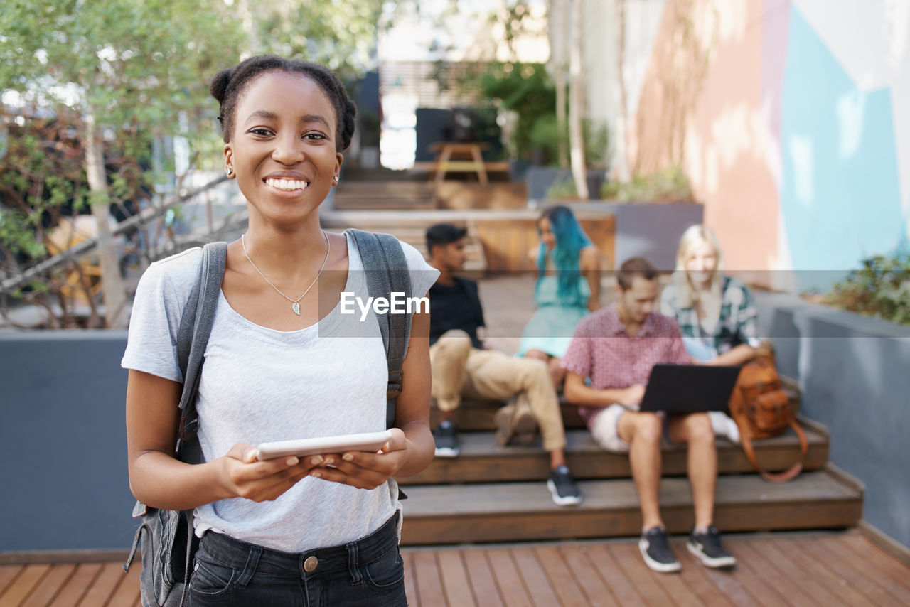 Portrait of young woman using digital tablet outdoors