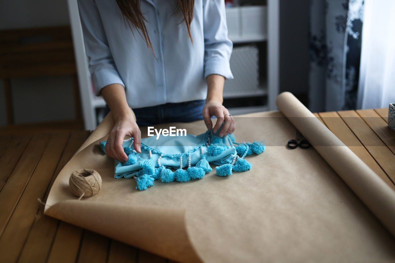 Woman packs a handicraft thing into craft paper, a small business and customer care.