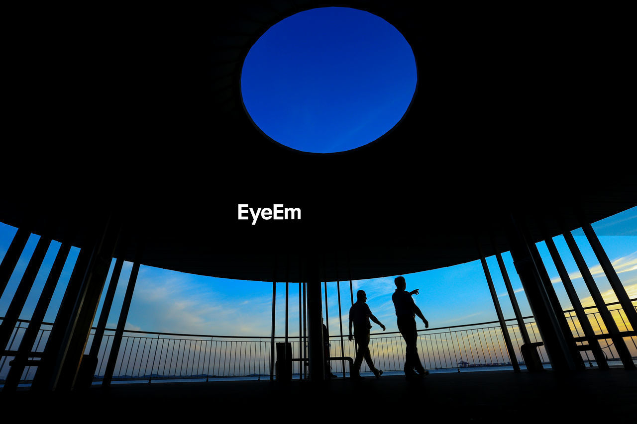 Silhouette people standing against blue sky