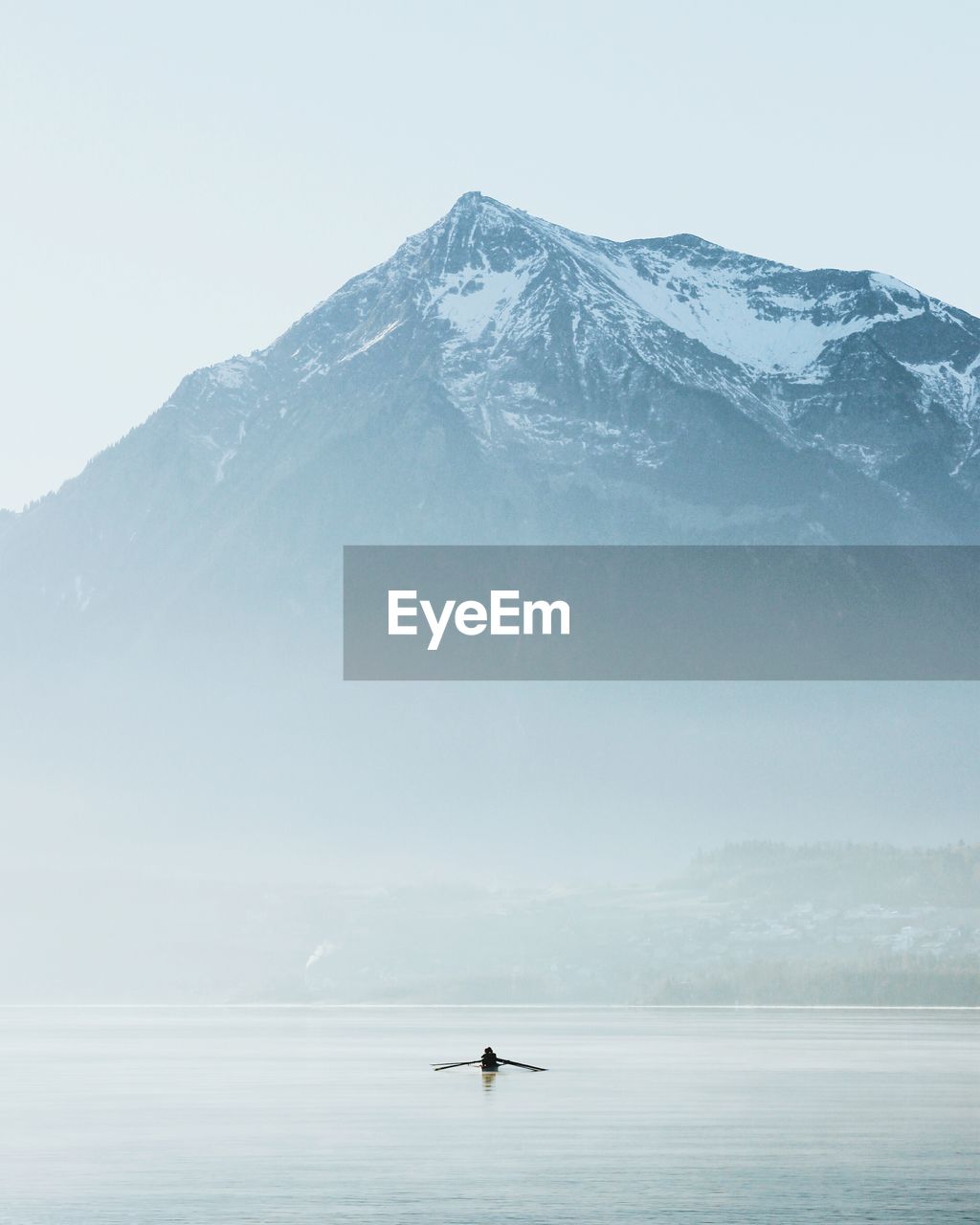 Scenic view of sea and mountains against sky during foggy weather