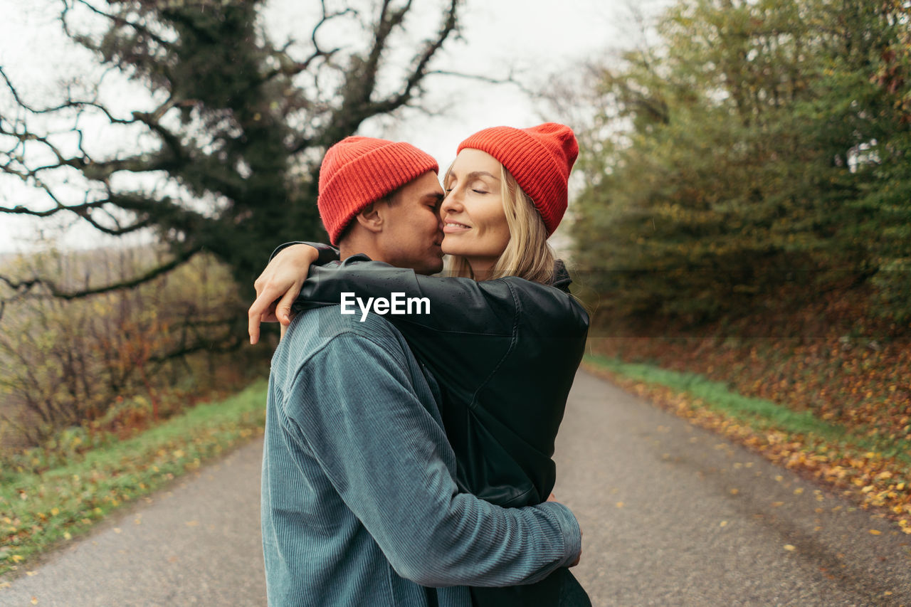 A young man hugs and kisses his girlfriend outside. relationships of modern lovers.