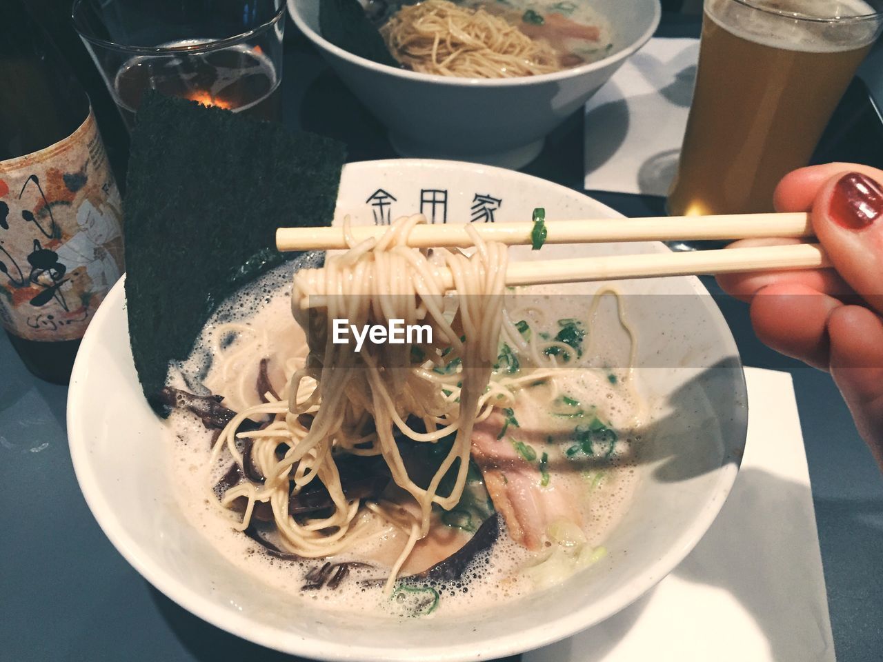 Cropped image of woman hand having ramen noodles with beer