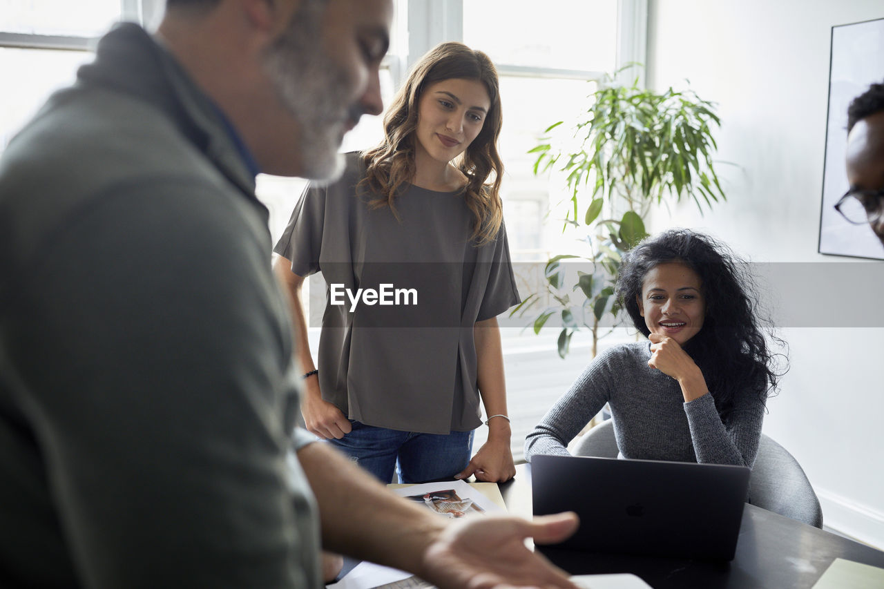 Businessman explaining to female colleagues in creative office