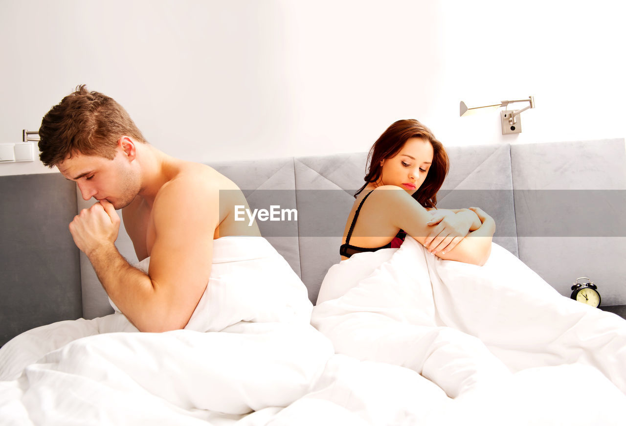Young couple in blanket on bed at home