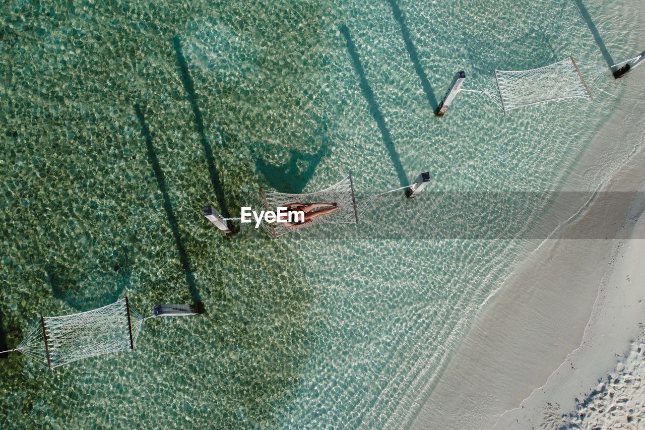 Attractive woman relaxing on a hammock over the water. air view.