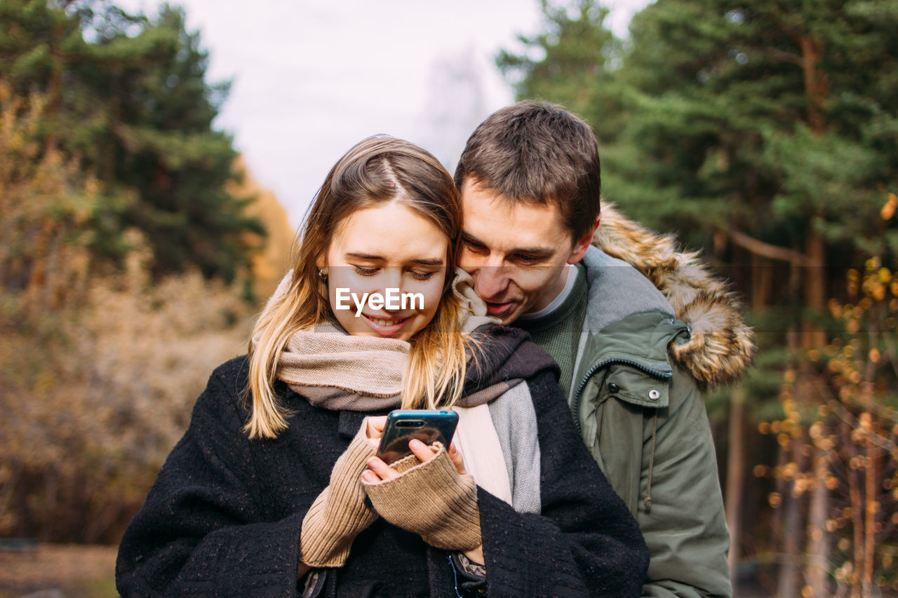 Man looking while woman using smart phone at park