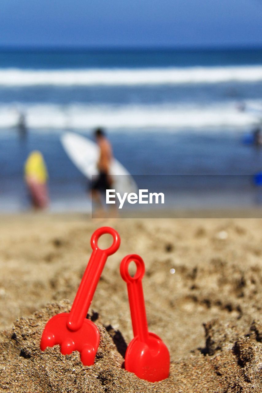 Close-up of red shovel in sand