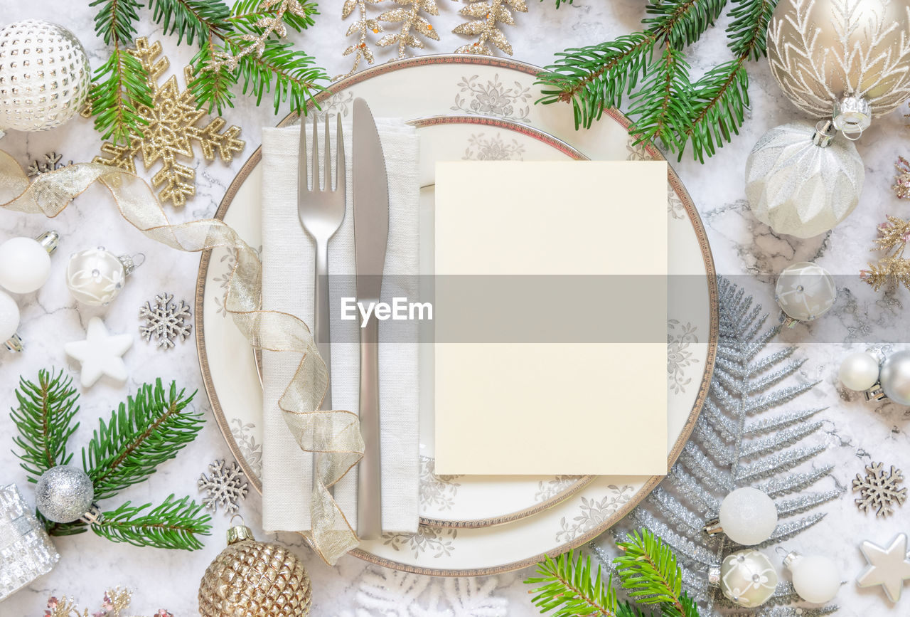 Festive table setting with plates, cutlery, ornaments and fir tree branches top view