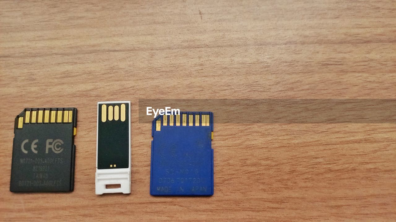 wood, flash memory, indoors, no people, table, still life, directly above, computer data storage, electronic device, memory card, high angle view, close-up, text, communication