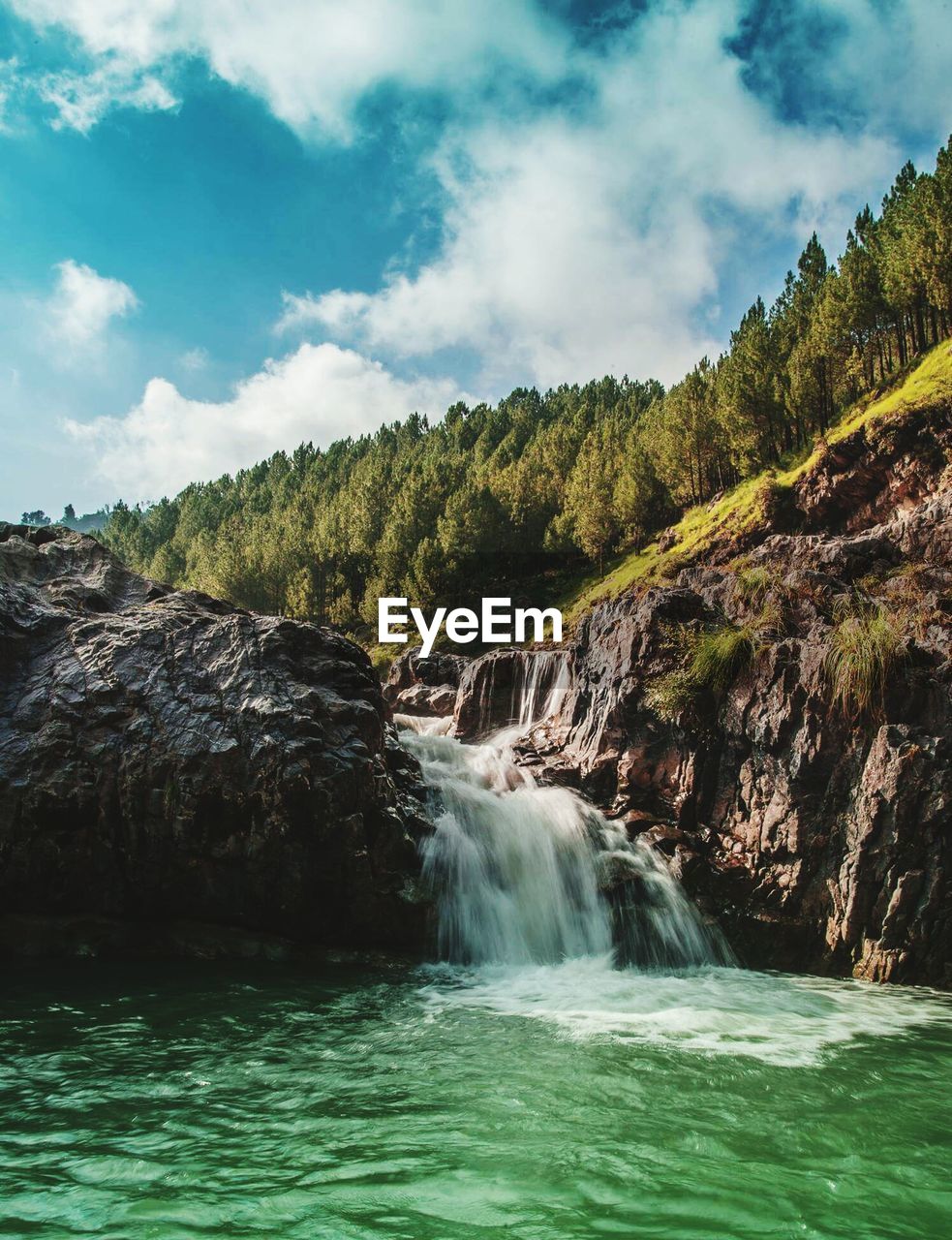 View of waterfall against cloudy sky