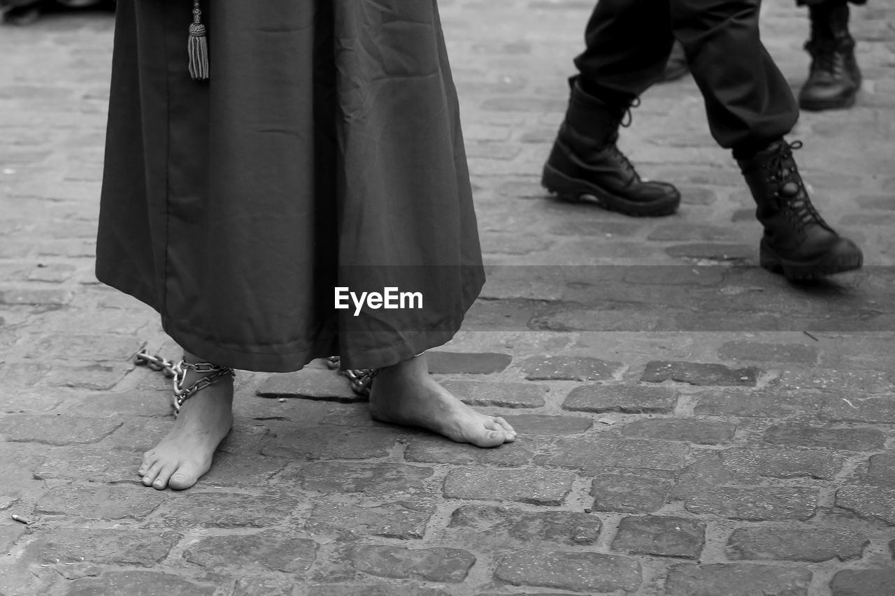 Low section of people standing on cobblestone