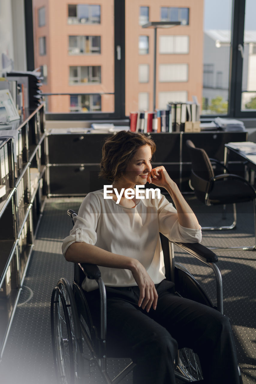 Disabled business woman sitting in wheelchair, smiling