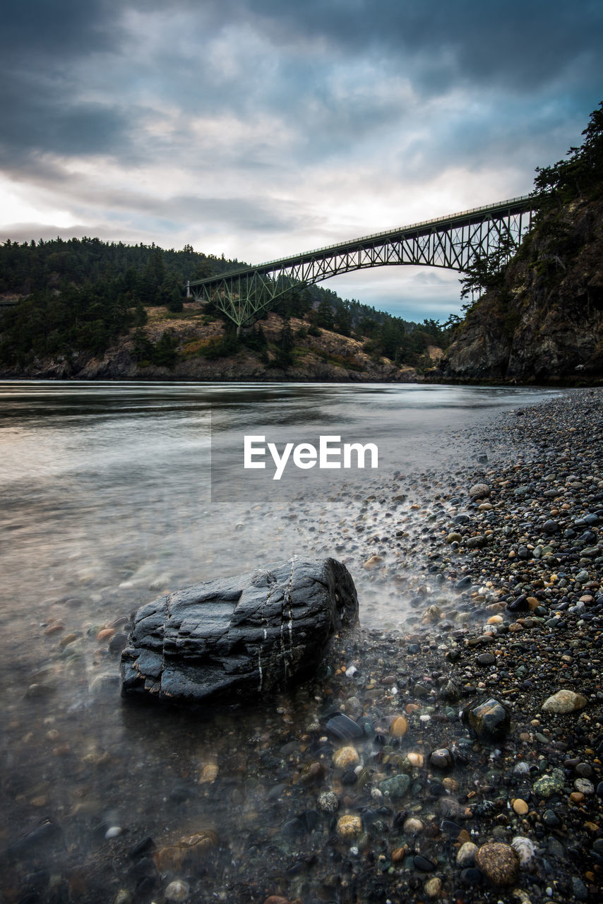 A rock on the shore with moody skies in deception pass state park