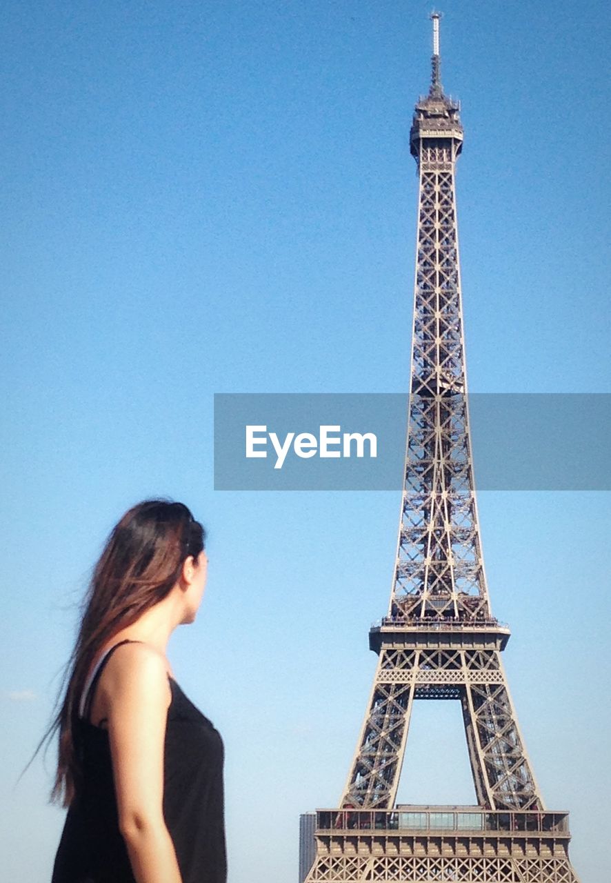 Woman standing by eiffel tower against sky