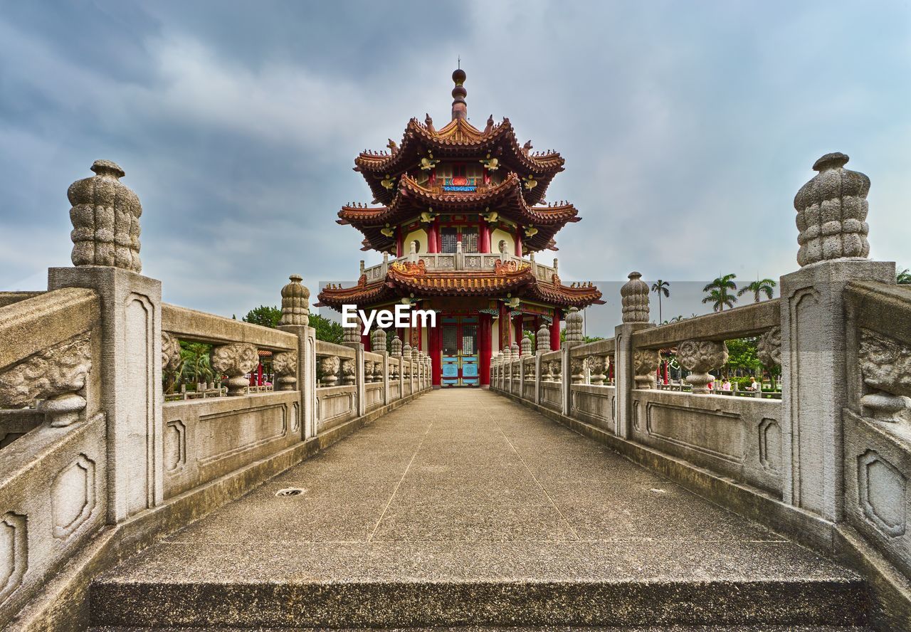 Footpath leading towards temple against sky