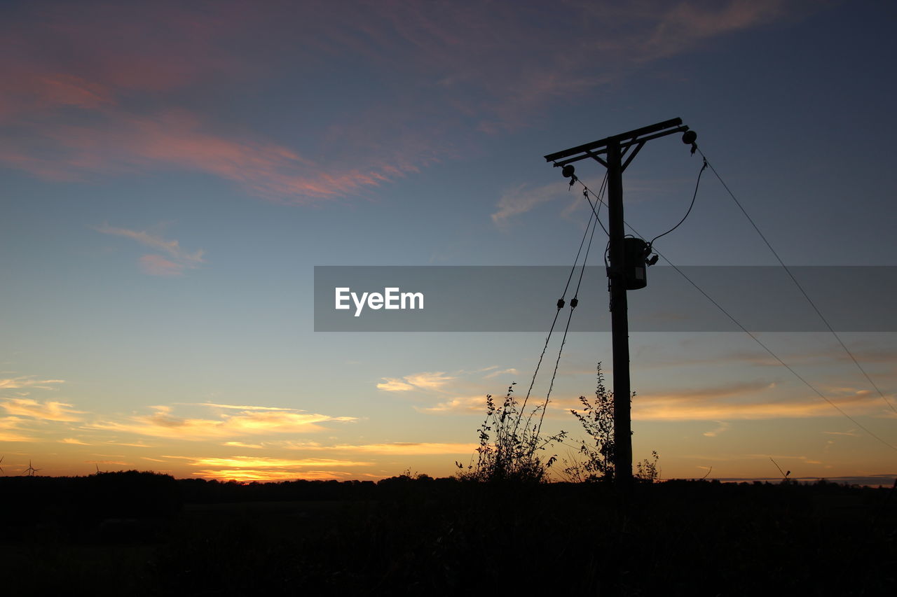 SILHOUETTE ELECTRICITY PYLON ON FIELD DURING SUNSET