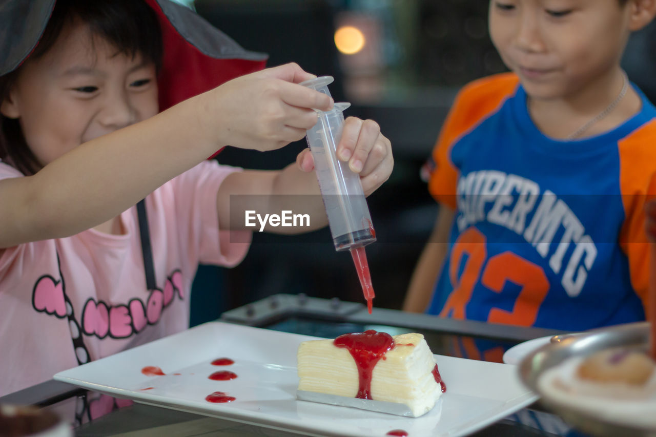 Cute siblings making cake on table