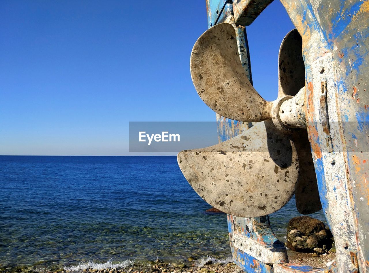 CLOSE-UP OF RUSTY CHAIN ON BEACH AGAINST CLEAR SKY