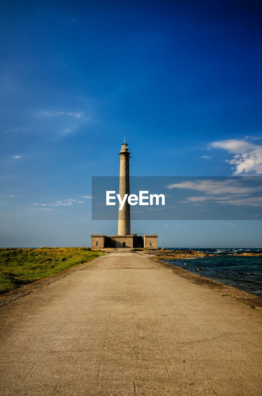 LIGHTHOUSE AMIDST SEA AGAINST BLUE SKY