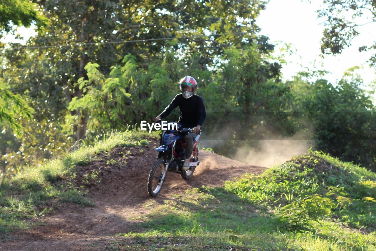 MAN RIDING BICYCLE ON ROAD IN FOREST