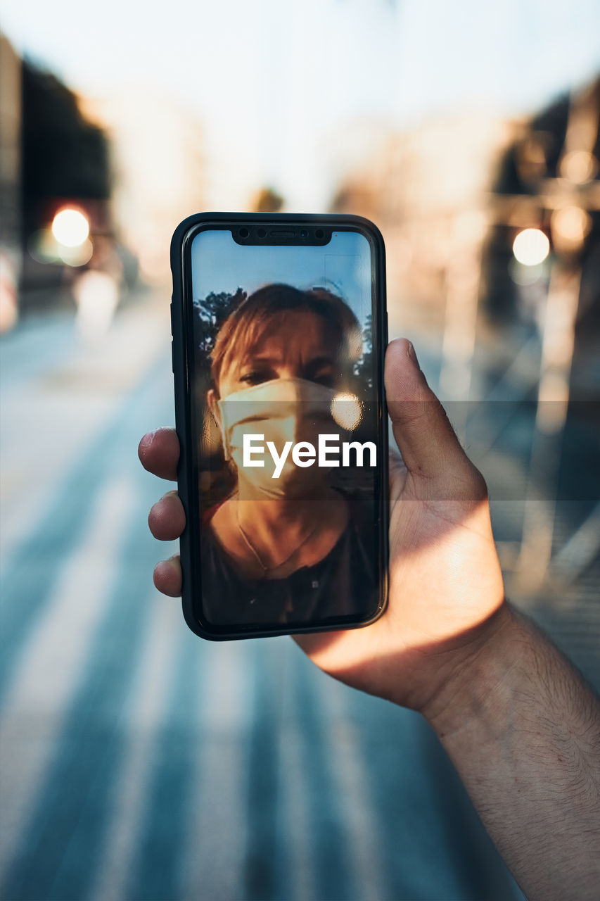 Young man having video call talking while walking downtown wearing the face mask to avoid virus