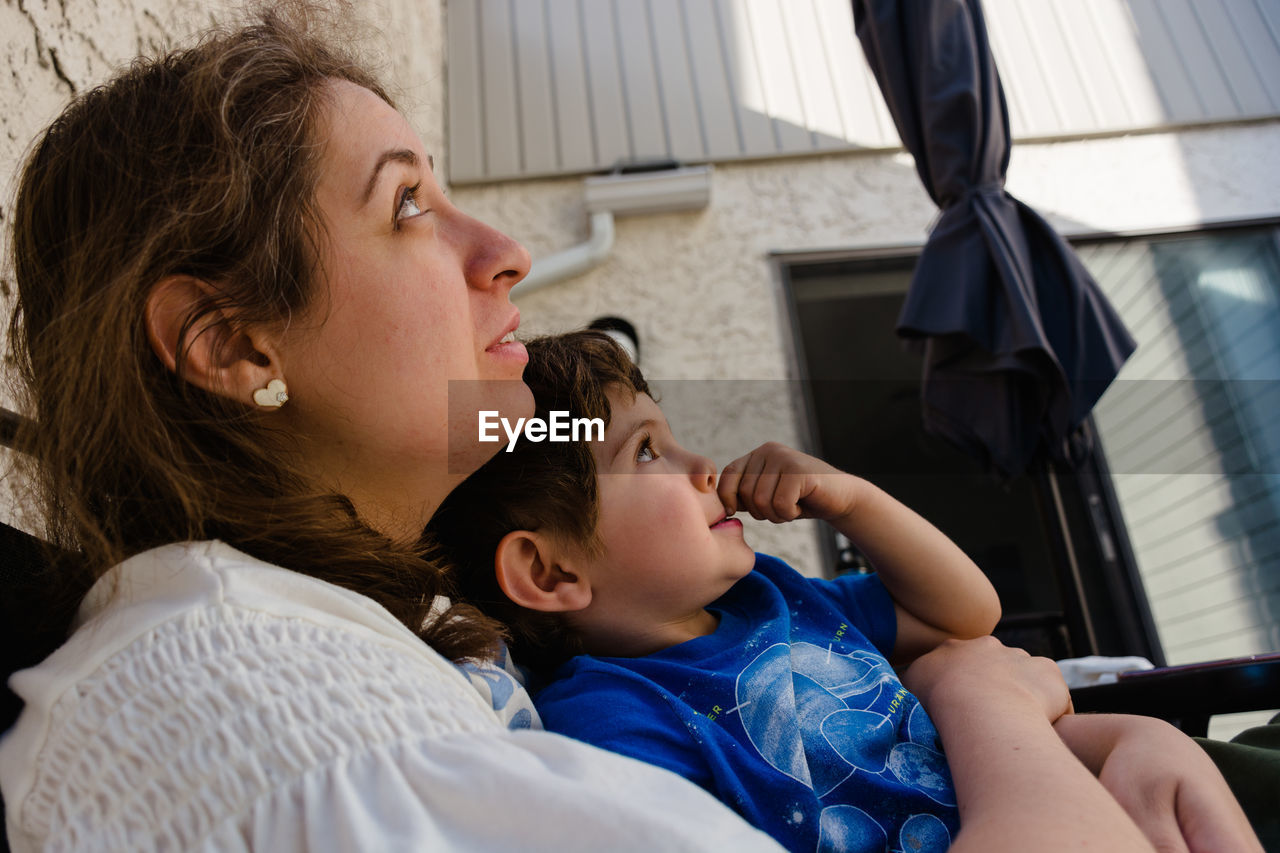 Mother and son looking up while sitting outdoors