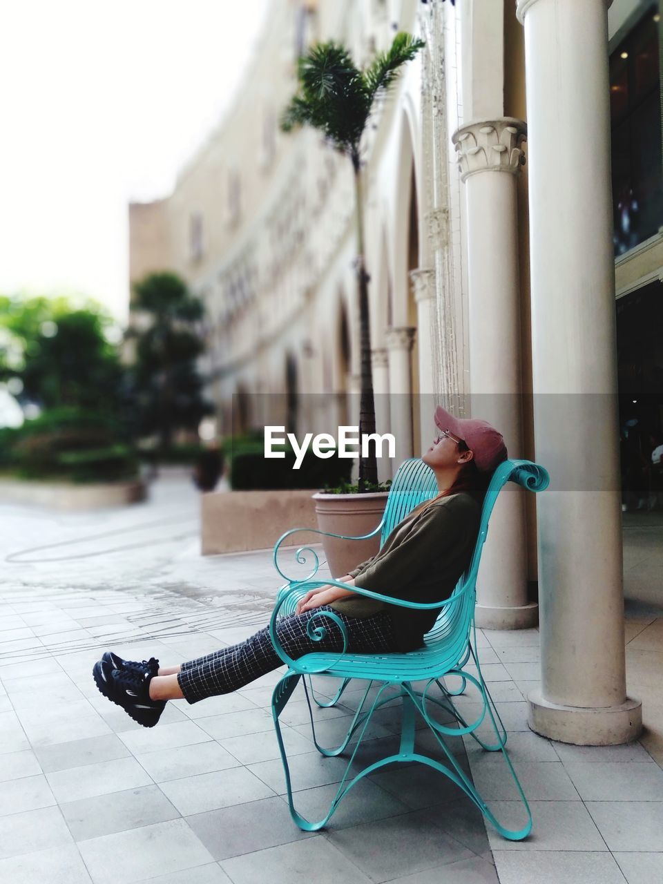 Woman looking up while relaxing on bench in city