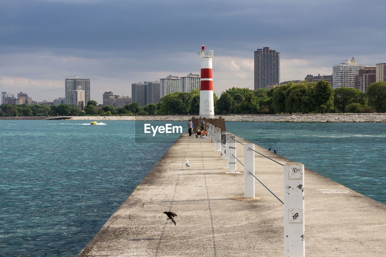 Pier leading towards lighthouse against sky