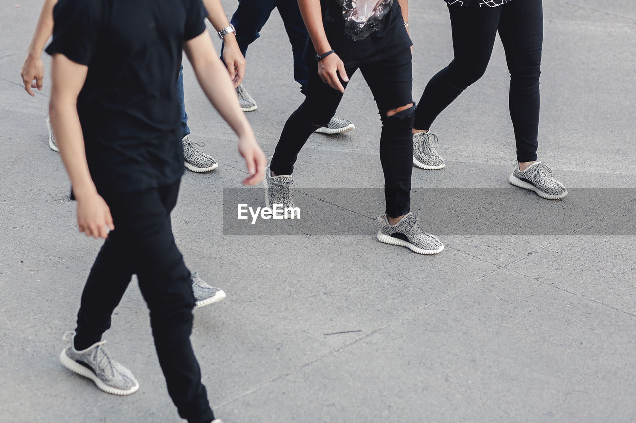 Low section of people walking on road wearing sports shoe