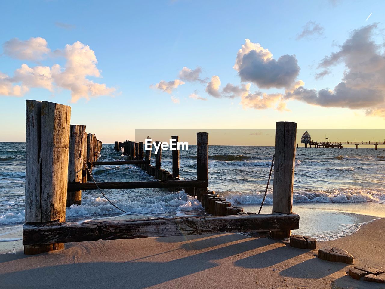 Wooden posts on beach against sky