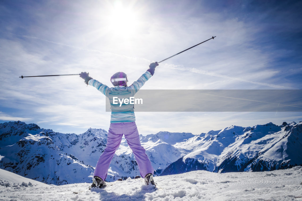 Woman skiing on snowy field during sunny day