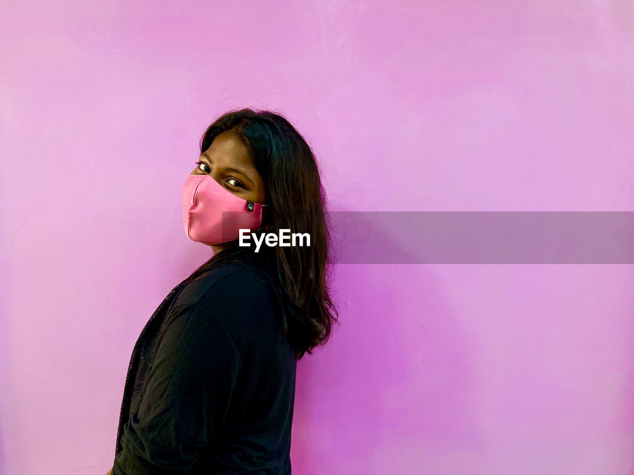 Portrait of young woman standing against wall