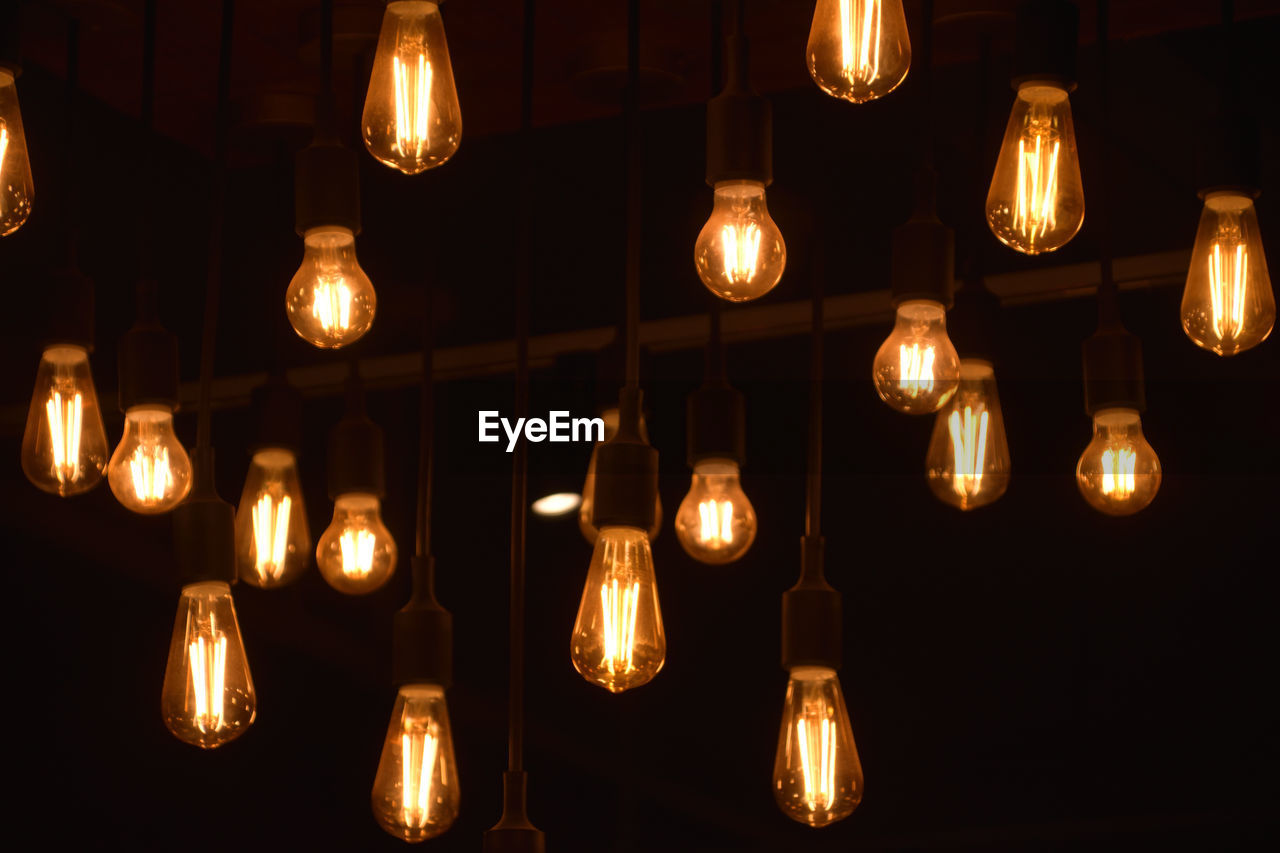 Illuminated light bulbs hanging at night