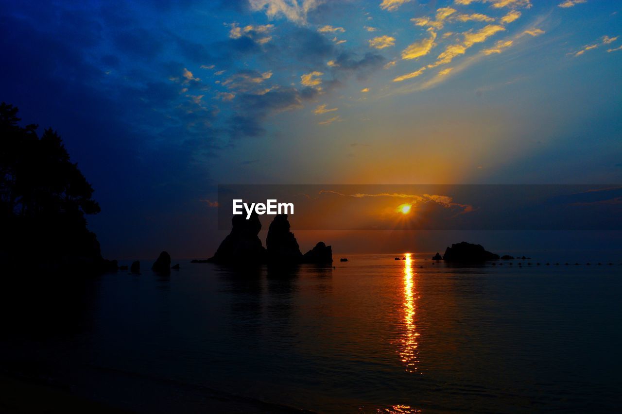 Silhouette of people on water at sunset