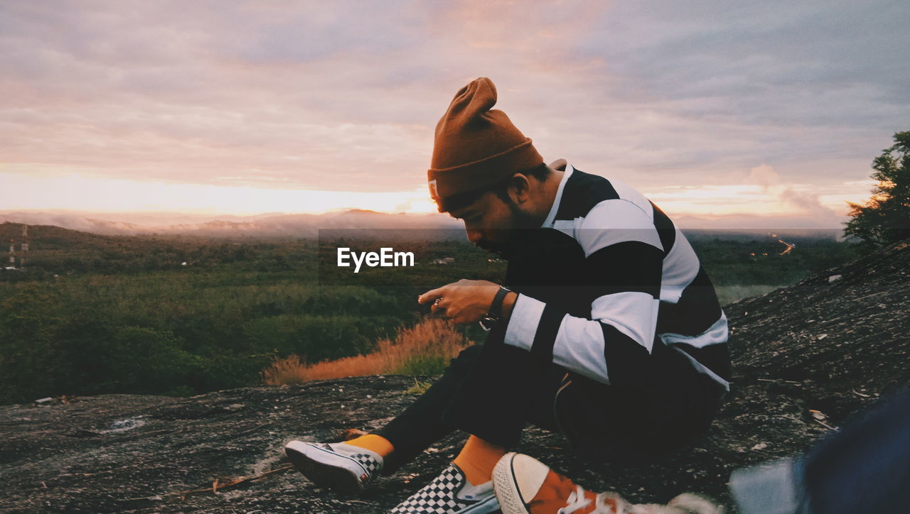 SIDE VIEW OF MAN ON FIELD DURING SUNSET