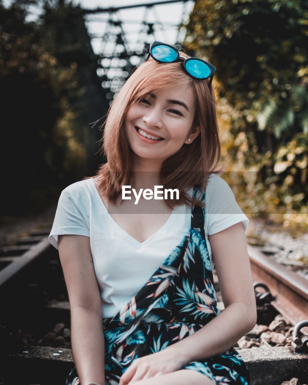 Portrait of young woman sitting on railroad track