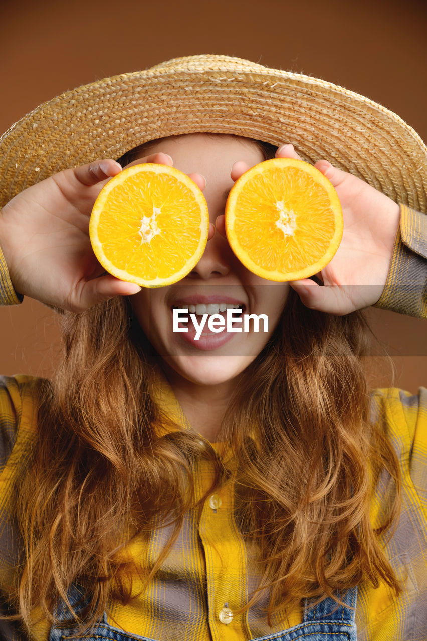 Attractive young woman in a straw hat laughs rejoicing in the summer, closing her eyes with halves 