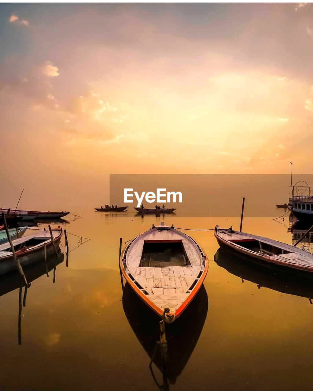 Boat moored in sea against sky during sunset