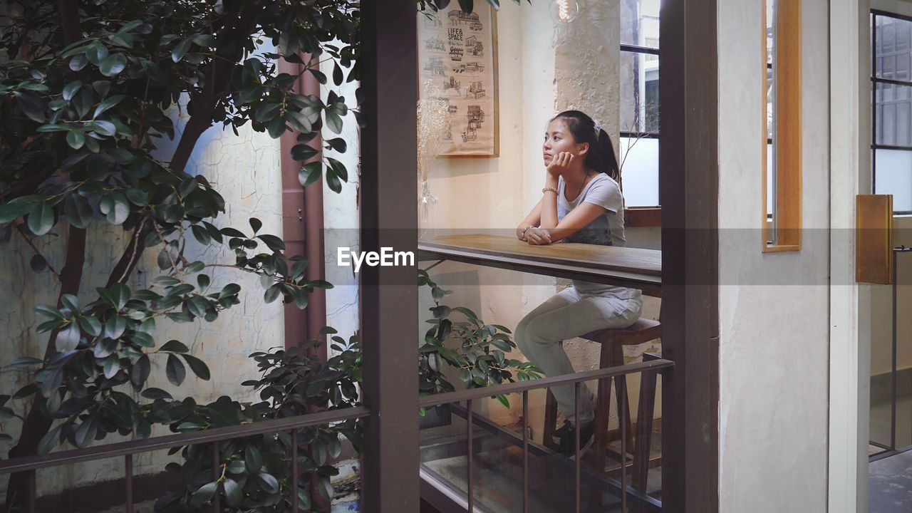 Thoughtful young woman sitting by window