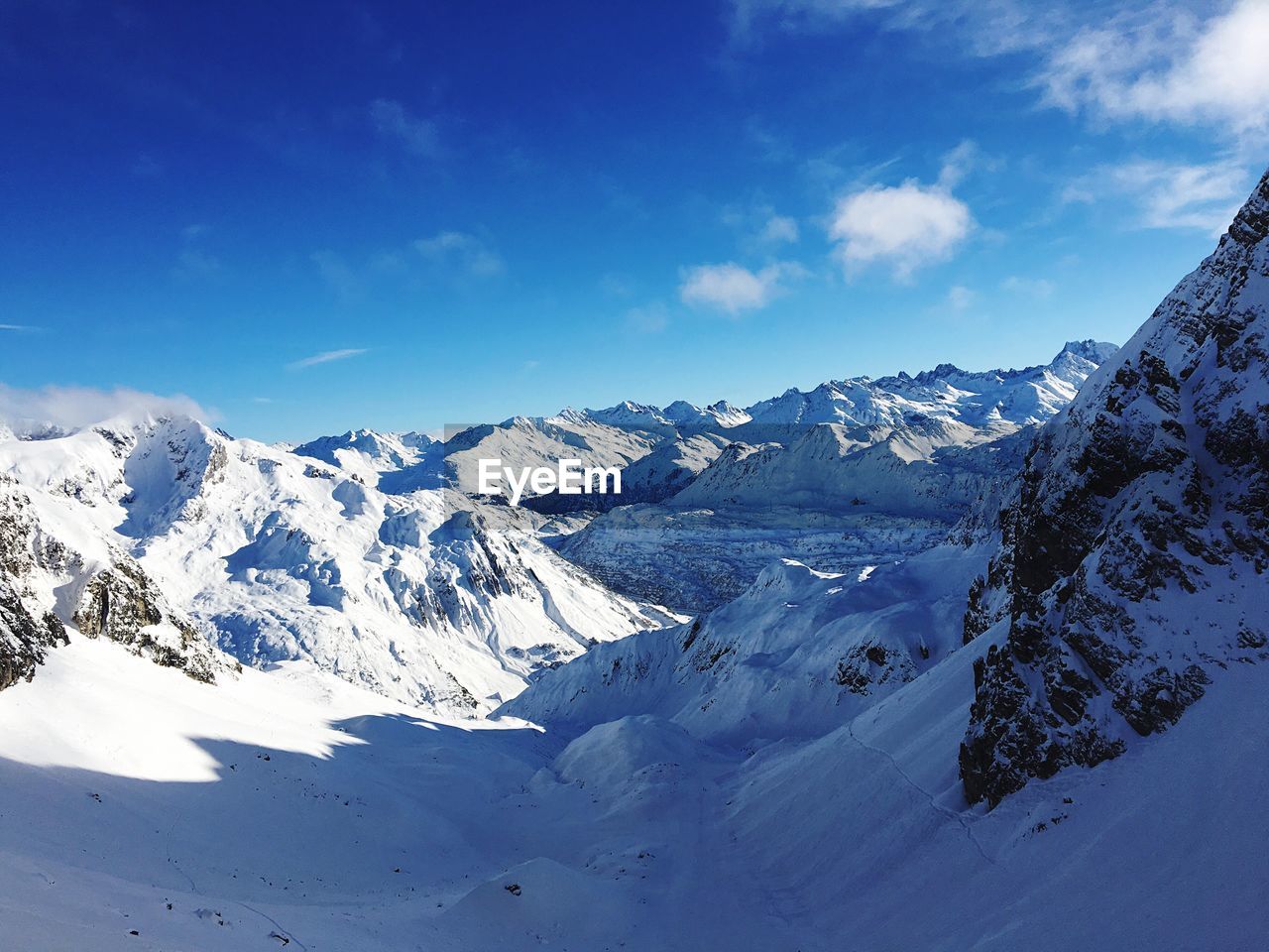 Scenic view of snow covered mountains against blue sky