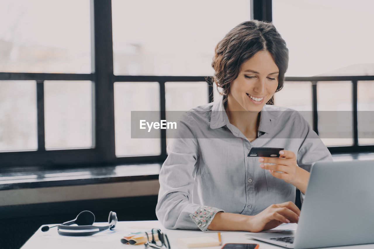 young businesswoman using laptop while sitting at office