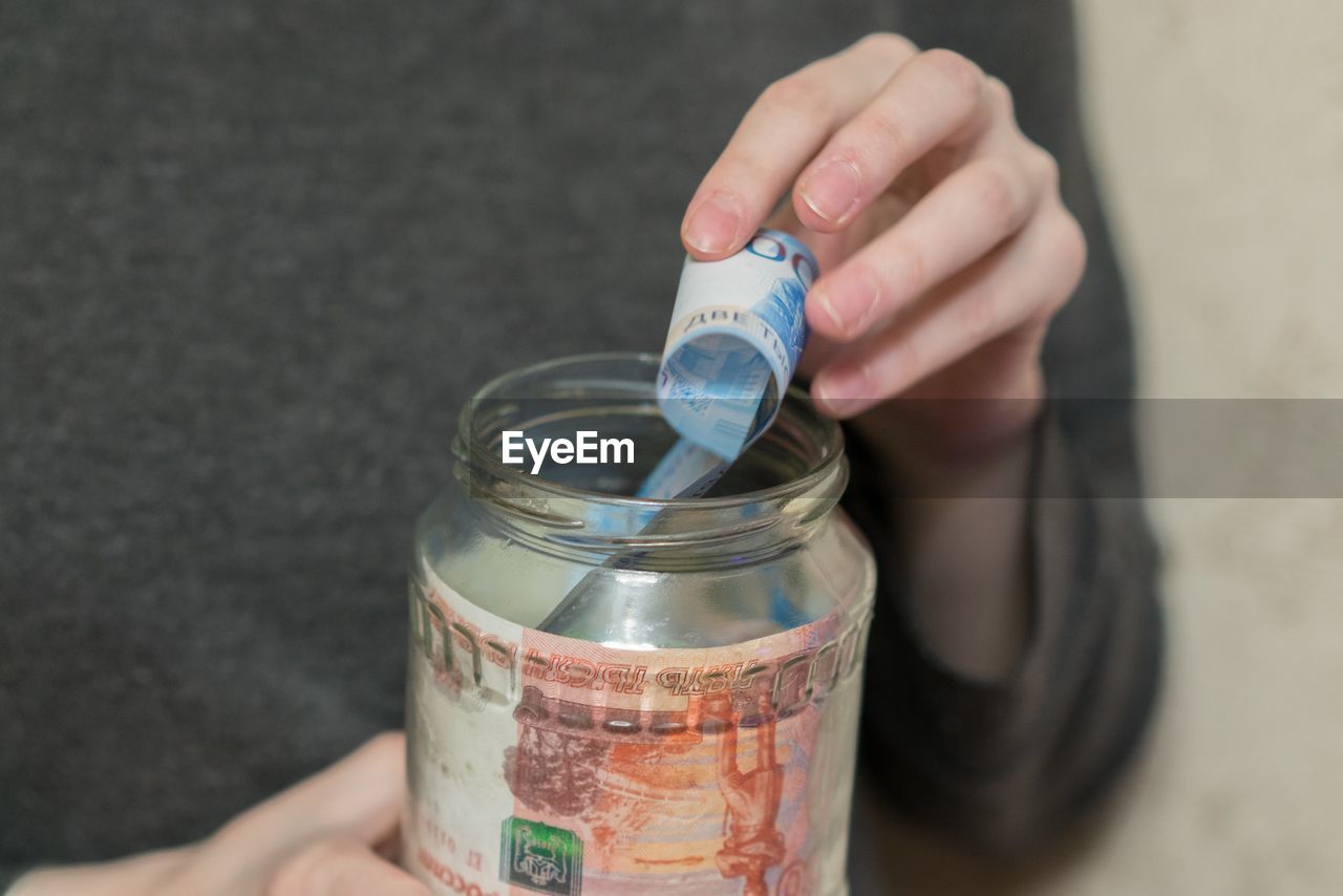 Midsection of woman removing paper currency from jar