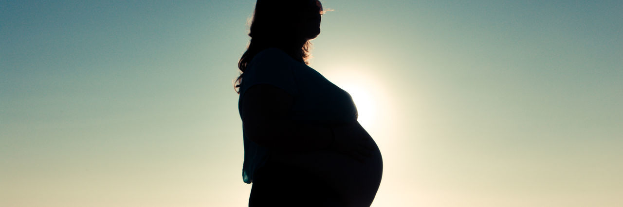 Midsection of pregnant woman against clear sky