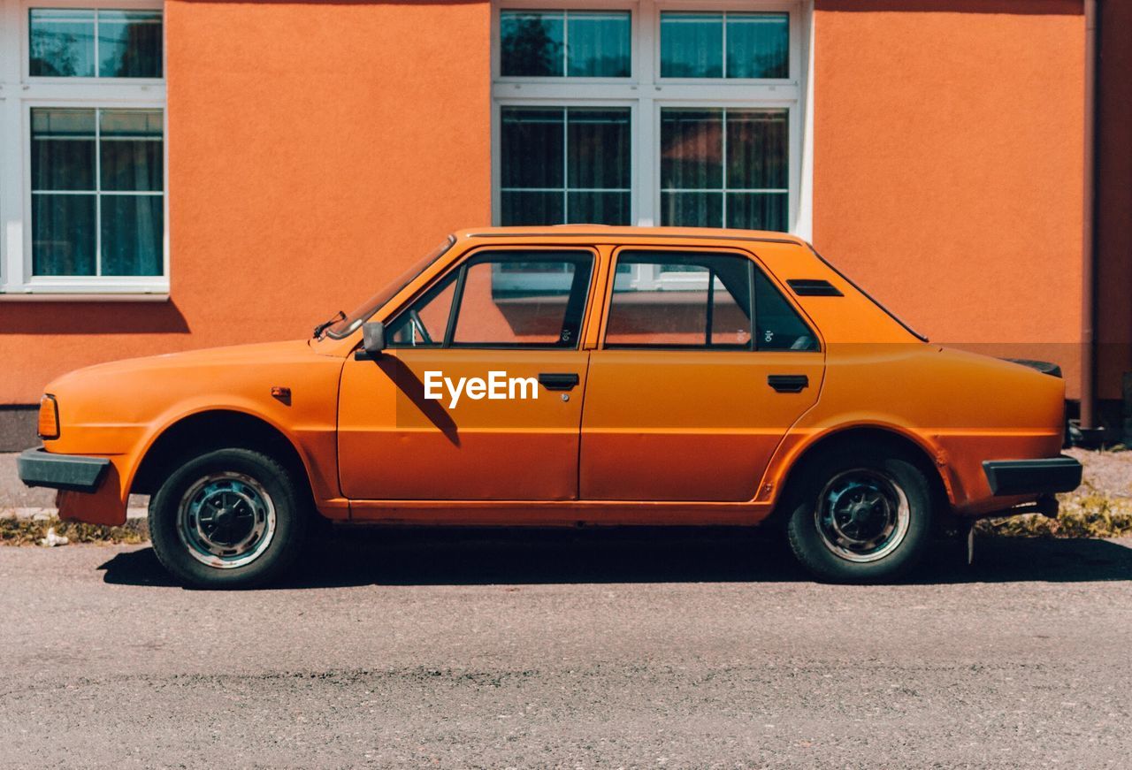 VINTAGE CAR PARKED AGAINST YELLOW WALL