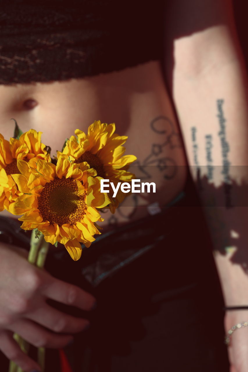 Midsection of woman holding sunflowers